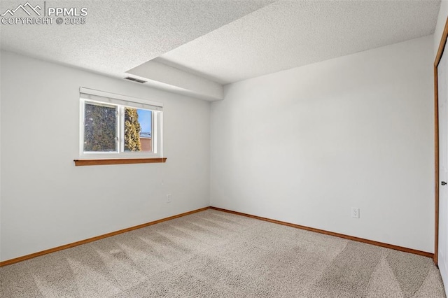 empty room featuring carpet, visible vents, a textured ceiling, and baseboards