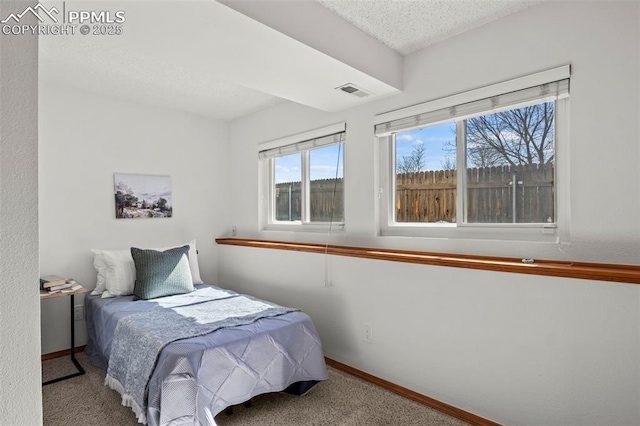 bedroom featuring a textured ceiling, carpet flooring, visible vents, and baseboards