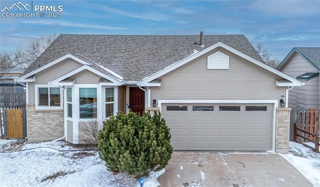 view of front facade featuring concrete driveway, brick siding, roof with shingles, and fence