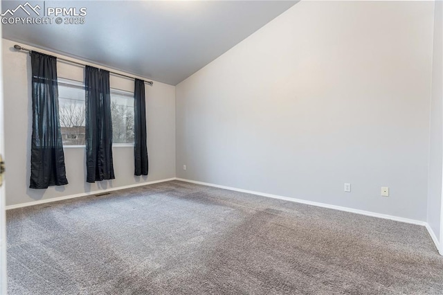 empty room with carpet floors, vaulted ceiling, and baseboards