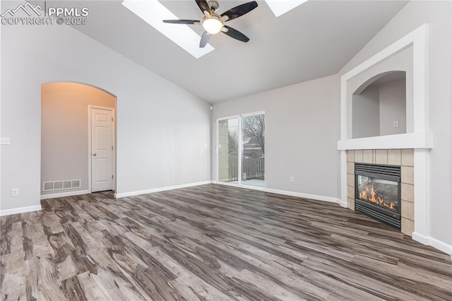 unfurnished living room featuring a tile fireplace, visible vents, vaulted ceiling, and wood finished floors