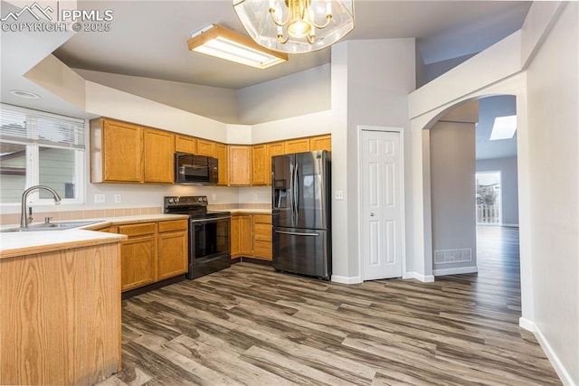 kitchen with dark wood-type flooring, a sink, visible vents, light countertops, and black appliances