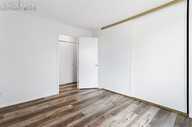 unfurnished bedroom with a closet, baseboards, and wood finished floors