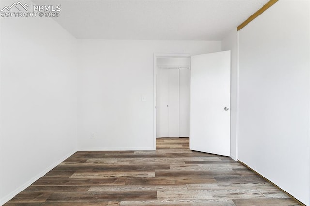 unfurnished bedroom featuring a closet, baseboards, and wood finished floors