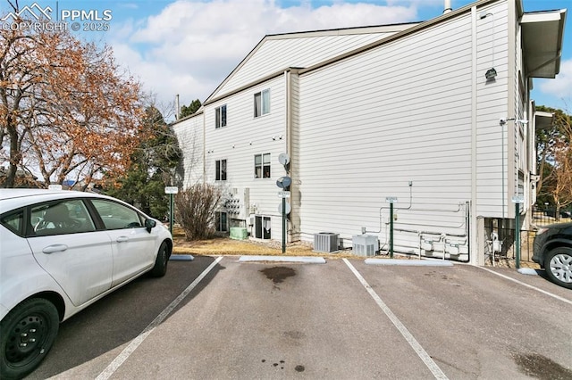 view of side of property featuring uncovered parking and central AC