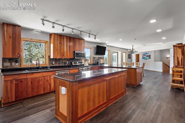 kitchen with brown cabinets, a center island, a peninsula, stainless steel appliances, and a sink