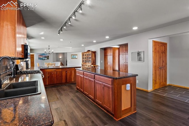 kitchen featuring brown cabinets, dark wood-type flooring, a peninsula, an inviting chandelier, and recessed lighting