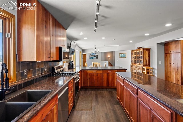 kitchen featuring dark wood-style floors, brown cabinets, decorative backsplash, appliances with stainless steel finishes, and a sink