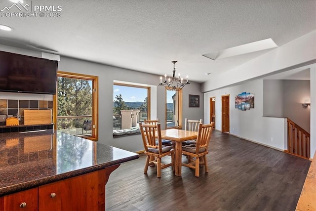 dining space featuring a textured ceiling, dark wood-type flooring, a notable chandelier, and baseboards