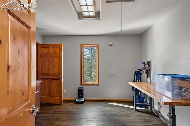 interior space featuring dark wood-style floors, electric panel, baseboards, and a textured ceiling