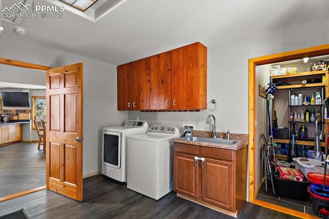 laundry room with cabinet space, baseboards, dark wood-type flooring, washer and dryer, and a sink