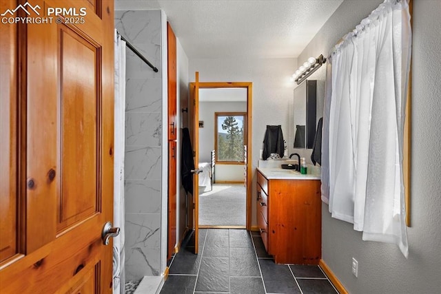 bathroom with a textured ceiling, a shower with shower curtain, vanity, baseboards, and tile patterned floors