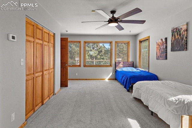 bedroom featuring a ceiling fan, a closet, light carpet, and baseboards