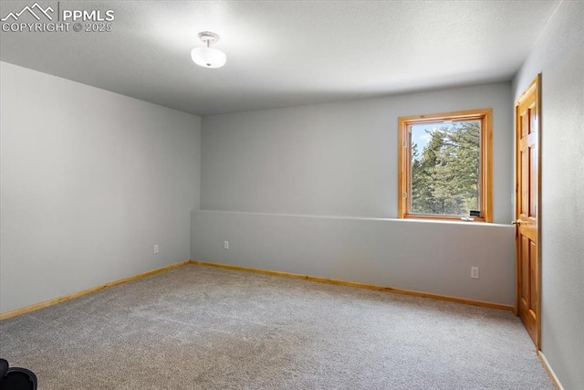 unfurnished room featuring a textured ceiling, carpet floors, and baseboards