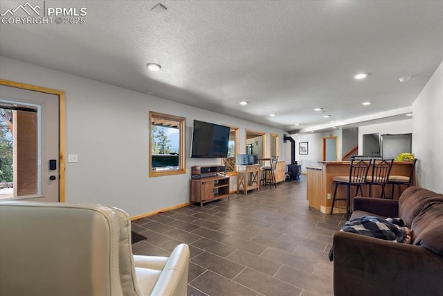 living area featuring a dry bar, recessed lighting, a textured ceiling, dark tile patterned flooring, and baseboards