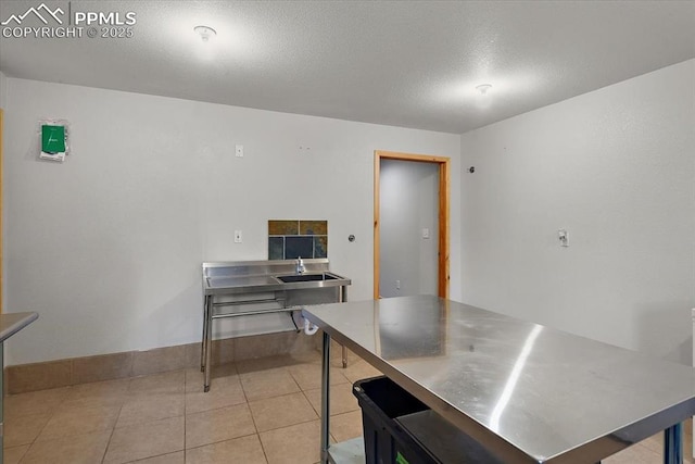 kitchen featuring stainless steel counters, a textured ceiling, and light tile patterned flooring