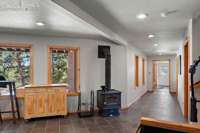 entrance foyer featuring a textured ceiling, recessed lighting, dark tile patterned floors, baseboards, and a wood stove