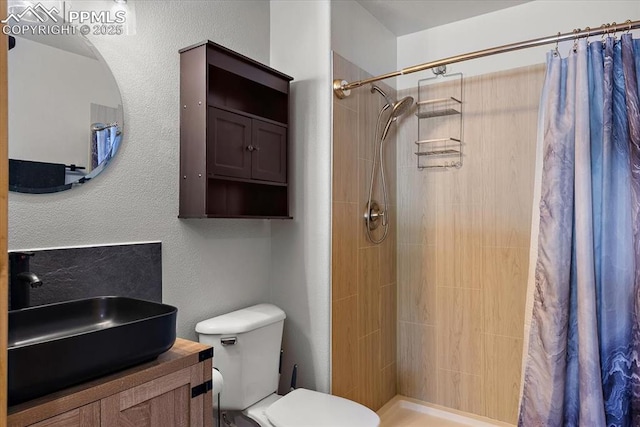 full bathroom featuring toilet, a tile shower, and vanity