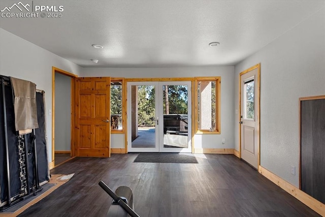 foyer featuring french doors, a textured ceiling, baseboards, and wood finished floors