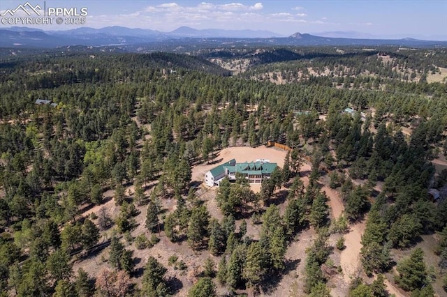 drone / aerial view featuring a mountain view and a view of trees