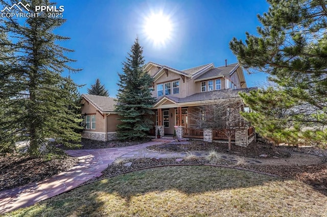 view of front of house featuring stone siding, covered porch, and stucco siding