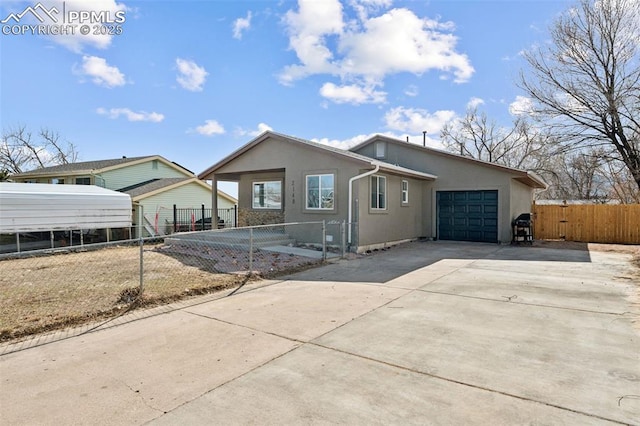 view of front of house with a fenced front yard, driveway, an attached garage, and stucco siding