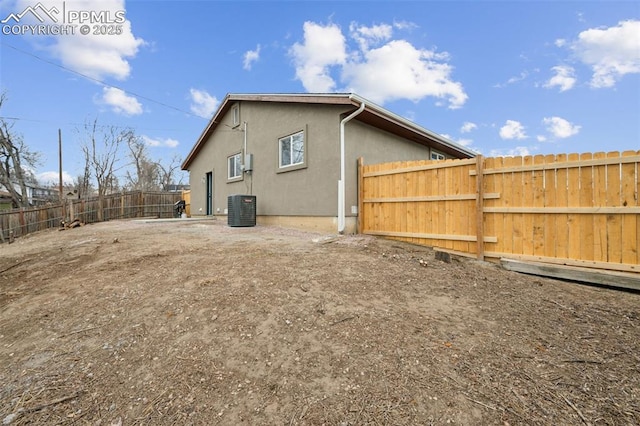 back of property with stucco siding, a fenced backyard, and central air condition unit