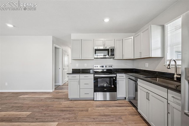 kitchen featuring light wood-style floors, appliances with stainless steel finishes, a sink, and recessed lighting