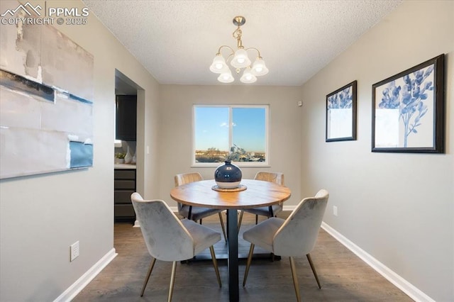 dining area with a textured ceiling, baseboards, and wood finished floors