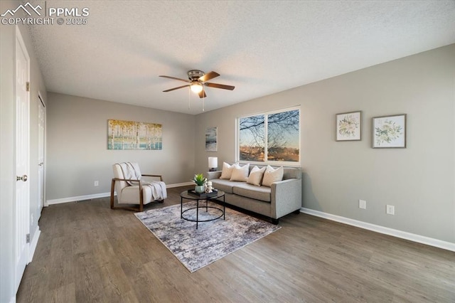 living room with a ceiling fan, a textured ceiling, baseboards, and wood finished floors