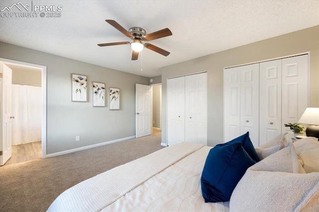 bedroom with carpet floors, a textured ceiling, baseboards, and two closets