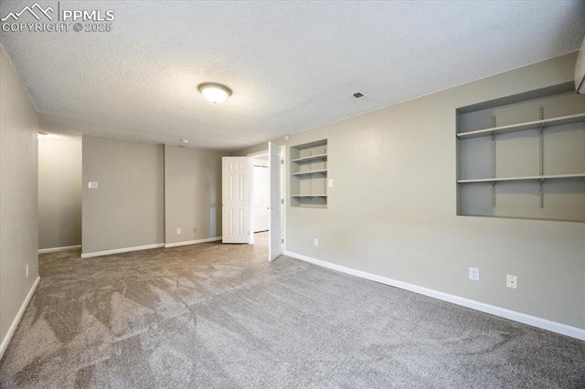 empty room with carpet floors, visible vents, a textured ceiling, and baseboards