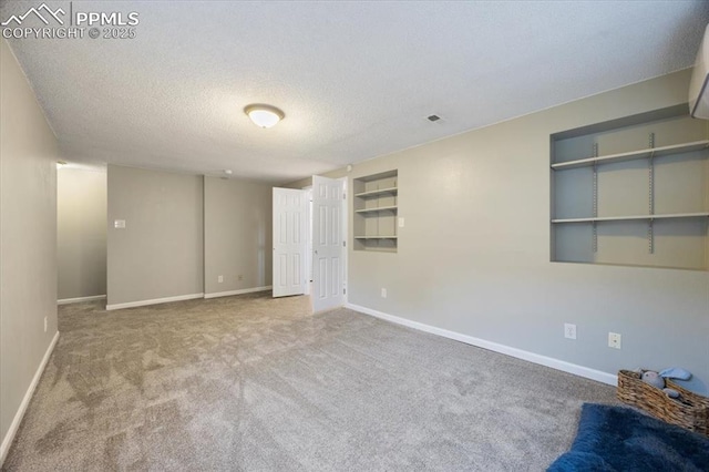 carpeted empty room with a textured ceiling, visible vents, and baseboards