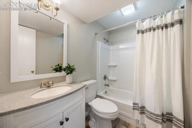 bathroom with a textured wall, shower / bathtub combination with curtain, toilet, and vanity