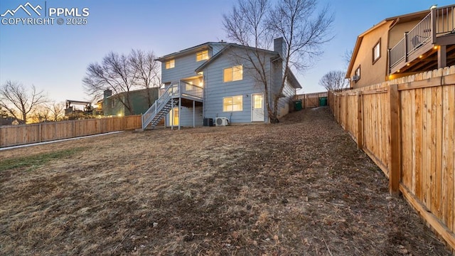 back of house featuring stairs, a chimney, and a fenced backyard