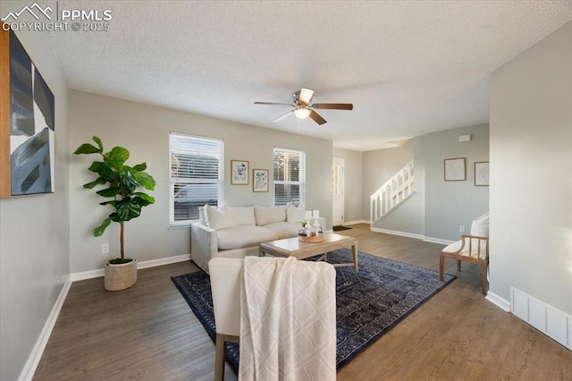 living area featuring visible vents, stairway, a textured ceiling, and wood finished floors