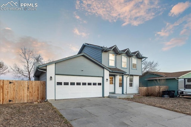 traditional-style home featuring an attached garage, fence, concrete driveway, and brick siding