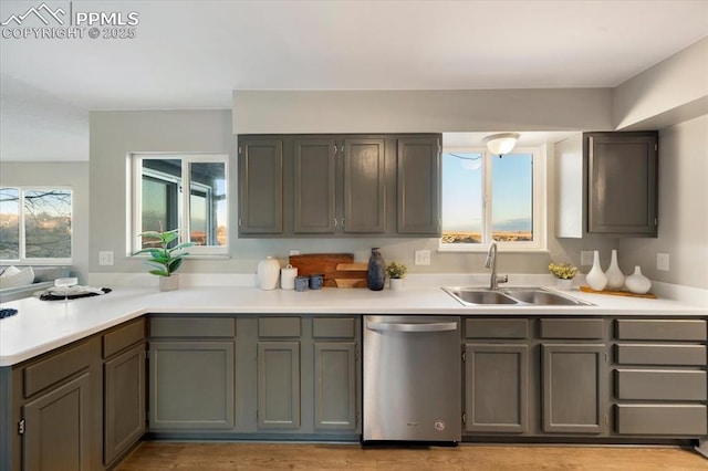 kitchen featuring a sink, a peninsula, light countertops, and stainless steel dishwasher