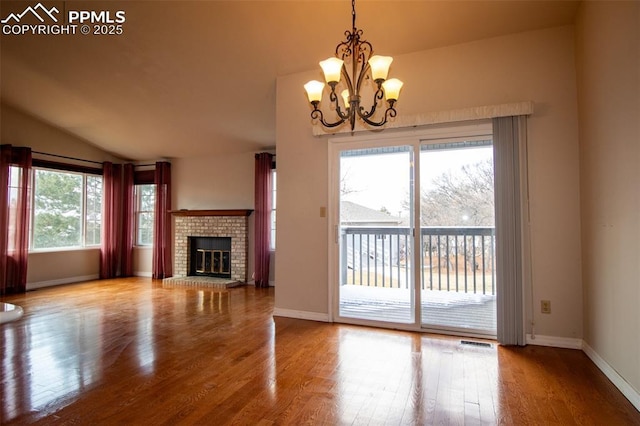 unfurnished living room featuring lofted ceiling, a fireplace, wood finished floors, visible vents, and baseboards