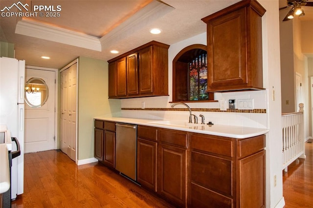 kitchen with ornamental molding, a raised ceiling, dishwasher, and wood finished floors