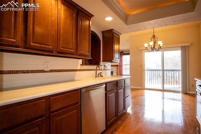 kitchen featuring a sink, wood finished floors, stainless steel dishwasher, decorative backsplash, and crown molding