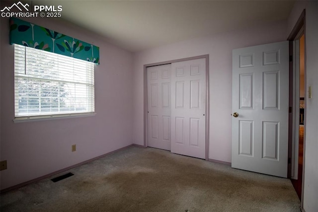 unfurnished bedroom with a closet, carpet flooring, visible vents, and baseboards