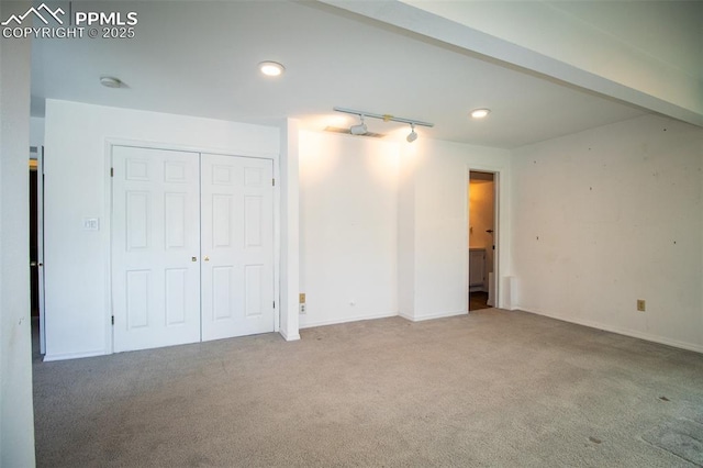 interior space featuring carpet floors, rail lighting, and baseboards