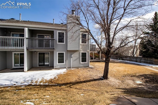 back of property featuring a balcony, a chimney, and fence