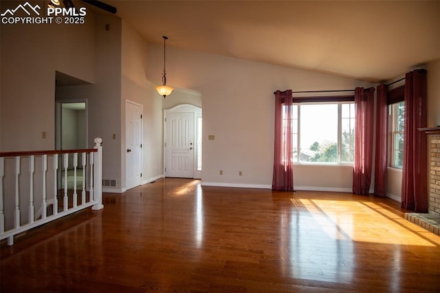 interior space featuring a fireplace, visible vents, wood finished floors, high vaulted ceiling, and baseboards