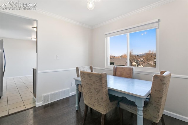 dining room with baseboards, visible vents, wood finished floors, and ornamental molding