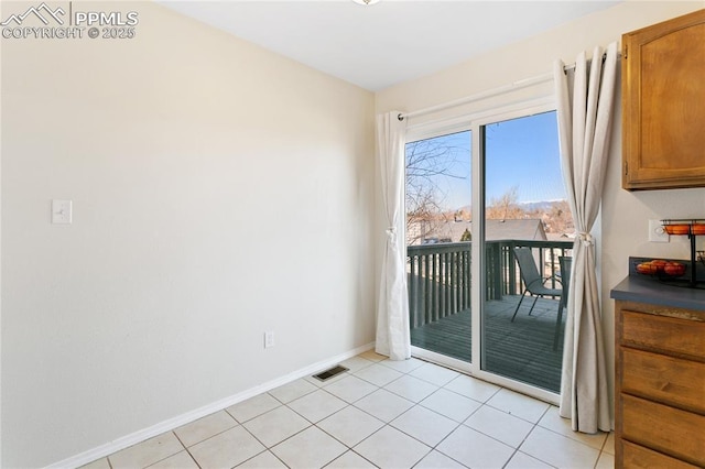 unfurnished room with baseboards, visible vents, and light tile patterned flooring