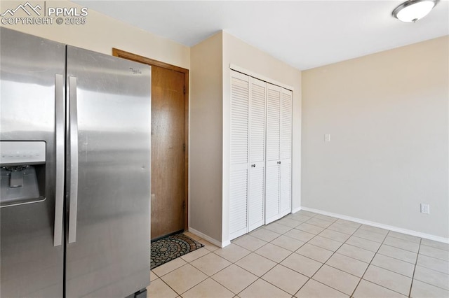 kitchen with light tile patterned flooring, stainless steel refrigerator with ice dispenser, and baseboards