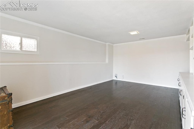 spare room featuring ornamental molding, dark wood-style flooring, and baseboards