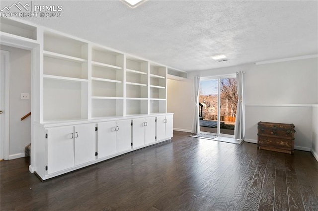 spare room featuring a textured ceiling, dark wood-type flooring, and baseboards